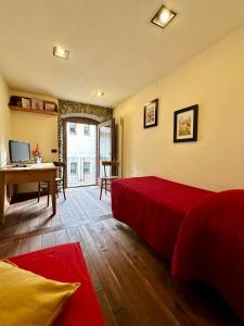 Schlafzimmer mit einem roten Bett und einem Schreibtisch in der Unterkunft Maison Rosset agriturismo, CAMERE, appartamenti e spa in Valle d'Aosta in Nus