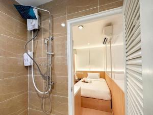 een badkamer met een douche, een bed en een spiegel bij Thrive Hotel in Bangkok