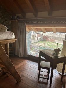 ニュスにあるMaison Rosset agriturismo, CAMERE, appartamenti e spa in Valle d'Aostaのテーブルとベッド、窓が備わる客室です。
