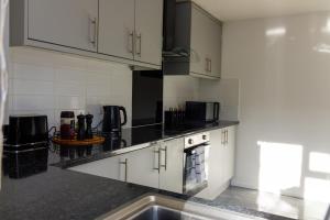una cocina con armarios blancos y encimeras negras en Central Home in Milton Keynes, en Milton Keynes