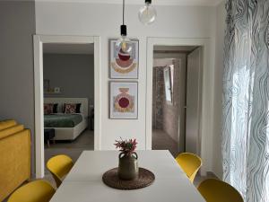 uma sala de jantar com uma mesa branca e cadeiras amarelas em Volturno3 Suites & more em Mazara del Vallo