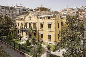 a large yellow building in a city at Hospes Palacio de los Patos, a Member of Design Hotels in Granada