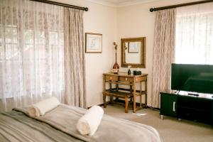 a bedroom with a bed and a television and a table at Thatchings Guest House in Nottingham Road