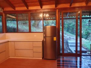 a kitchen with a refrigerator and some windows at Finca Las Palmas Ecolodge in Puyo