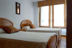a hotel room with two beds and a window at Piso espacioso en el centro con plaza de garage in Ribeira