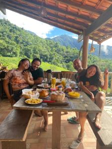 a group of people sitting around a table with food at Recanto bela Vista caminho do ouro in Paraty
