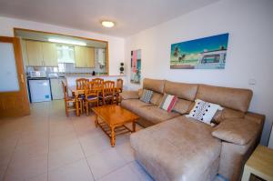 ein Wohnzimmer mit einem Sofa und einem Tisch sowie eine Küche in der Unterkunft CALA VENT MAR Y SOL Poniente Beach in Benidorm