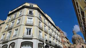 un edificio alto de color blanco con balcones y una cúpula en Apartamentos Almada, en Zaragoza