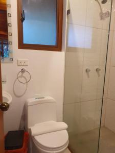 a bathroom with a toilet and a glass shower at Finca Las Palmas Ecolodge in Puyo
