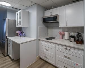 eine Küche mit weißen Schränken und einem Edelstahlkühlschrank in der Unterkunft Solara Studio with Pool/Hot tub/Parking/Gym in Canmore