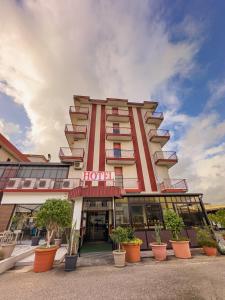 ein Hotelgebäude mit Topfpflanzen davor in der Unterkunft HOTEL 1+1 di C.Costabile & f.lli in Pontecagnano