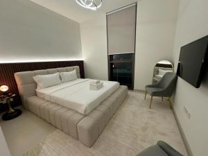 een slaapkamer met een groot wit bed en een televisie bij Luxury Apartment Burj Crown Burj Khalifa View in Dubai