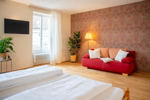 a bedroom with a red couch and a window at Biohotel Alte Post in Müllheim
