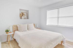 a white bedroom with a bed and a window at Central, Cozy Retreat in Vero Beach