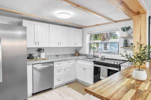 a kitchen with white cabinets and a wooden table at Central, Cozy Retreat in Vero Beach
