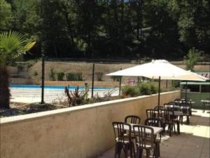 una fila de mesas y sillas con sombrilla junto a una piscina en chalets19hameauxduperrier.com, en Lissac-sur-Couze