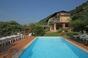 een zwembad met stoelen en een huis op de achtergrond bij Casale Massina APPARTAMENTO GIADA in Salò