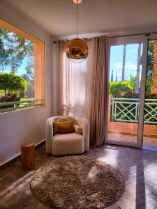 a living room with a chair and a large window at Appartement Oxygène Marrakech Sun in Marrakesh