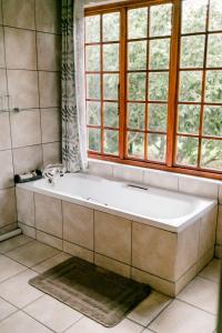 a bath tub in a bathroom with a window at Thatchings Guest House in Nottingham Road