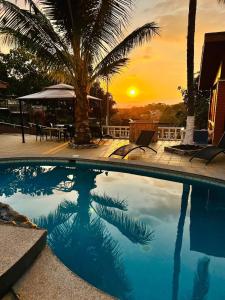a swimming pool with a sunset in the background at Uruka Lodge in Alajuela