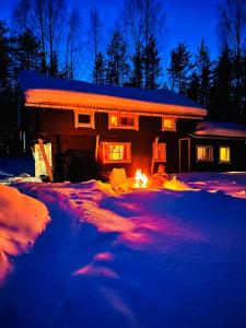 a house with a fire in front of it at night at Lakeside Log Villa Edith in Rovaniemi
