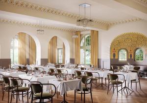 um salão de banquetes com mesas e cadeiras brancas em Grand Hotel Belvedere, a Beaumier Hotel & Spa em Wengen