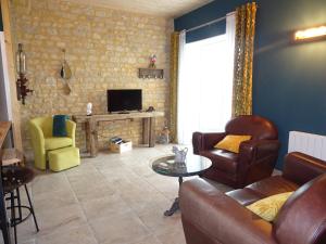 a living room with a couch and chairs and a television at La ferme aux chats in Formigny