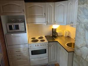 a kitchen with white cabinets and a stove and a microwave at Lakeside Log Villa Edith in Rovaniemi
