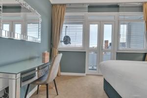 - une chambre avec un lit, un bureau et des fenêtres dans l'établissement Coastal Sunset By My Getaways, à Brighton et Hove