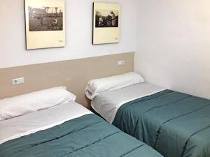 two beds in a room with pictures on the wall at ALOJAMIENTO NO ACTIVo in Moclín