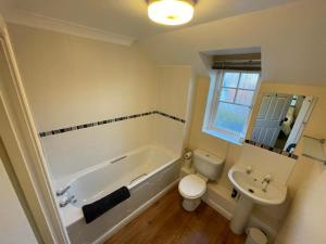 a bathroom with a tub and a toilet and a sink at Travaal.©om - 2 Bedroom Apartment - Farnborough in Farnborough