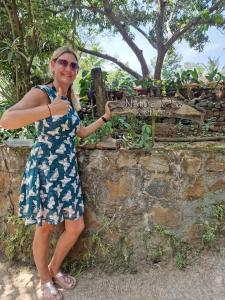a woman in a dress standing next to a stone wall at Nature Glow Cottage in Udawalawe