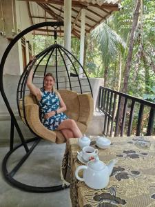 a woman sitting in a chair on a porch at Nature Glow Cottage in Udawalawe