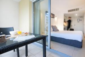 カーニュ・シュル・メールにあるNemea Appart Hotel Le Lido Cagnes sur Merのベッドルーム1室(ベッド1台、ガラステーブル付きのテーブル付)