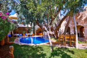 una piscina en un patio con árboles y sillas en Riad Dar Etto en Essaouira
