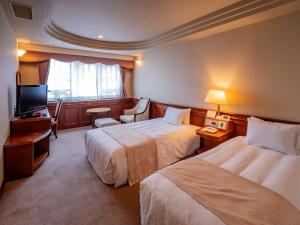 um quarto de hotel com duas camas e uma televisão em Hotel Fukiageso em Kagoshima