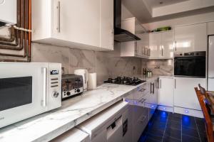 a kitchen with white marble counter tops and white appliances at Refined Comforts for Two Room 5 in Manchester