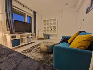 a living room with a blue couch and a tv at Flora furnished fair apartments in Essen