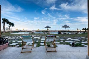 two chairs sitting on a patio with a large field with umbrellas at VESTA - Soma Bay Residence in Hurghada