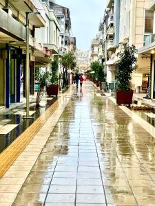 a city street in the rain with people walking with an umbrella at Modern Home Loft in Alexandroupoli