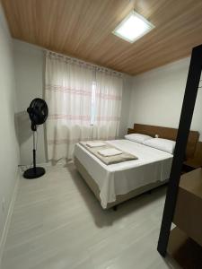 a bedroom with a large bed and a fan at Linda Casa Jardim - 500 Mts da Praia in Navegantes