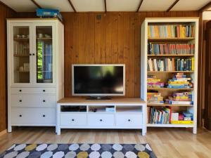 uma sala de estar com televisão e duas estantes de livros em Ferienhaus in der Natur em Schlossrued