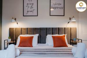 1 dormitorio con 1 cama grande con almohadas de color naranja en 20% off Monthly Stays 2 Bedroom Townhouse en Nottingham