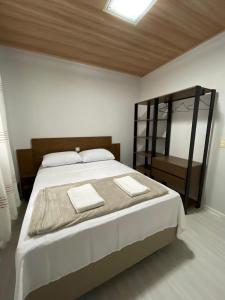 a bedroom with a large bed and a mirror at Linda Casa Jardim - 500 Mts da Praia in Navegantes