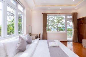 - une chambre avec un grand lit blanc et des fenêtres dans l'établissement Villa Trung Nghĩa 37, à Khu Chi Lăng 37 autres photos