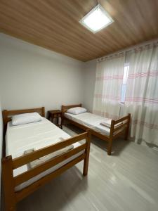 two beds in a room with a window at Linda Casa Jardim - 500 Mts da Praia in Navegantes