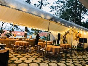 un homme debout sous une tente avec des tables et des chaises dans l'établissement Villa Trung Nghĩa 37, à Khu Chi Lăng