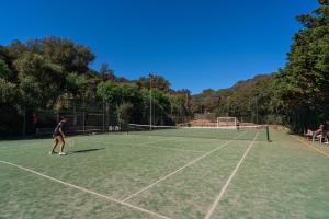 twee mensen die tennissen op een tennisbaan bij Stella del Mare Family Camping Village in Castiglione della Pescaia