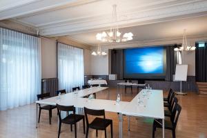 una sala de conferencias con mesas, sillas y una pantalla grande en Concept Hotel Landhaus, en Burgdorf