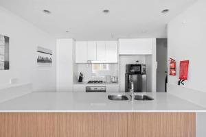 a white kitchen with a sink and a refrigerator at NEW 3BR Apt in Kingsgrove Sleeps 7 in Sydney